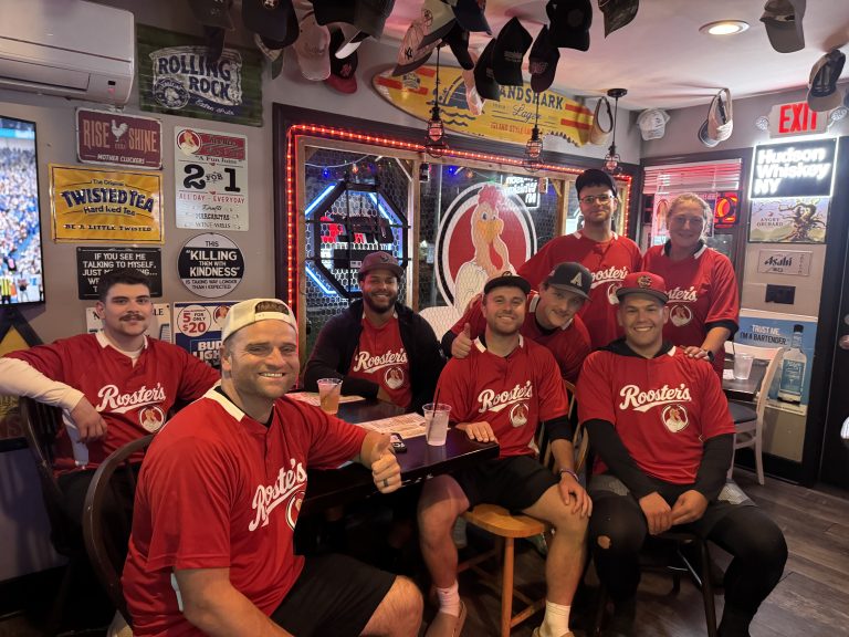 Group wearing red Rooster's jerseys gathered inside Rooster's Wings & Brew
